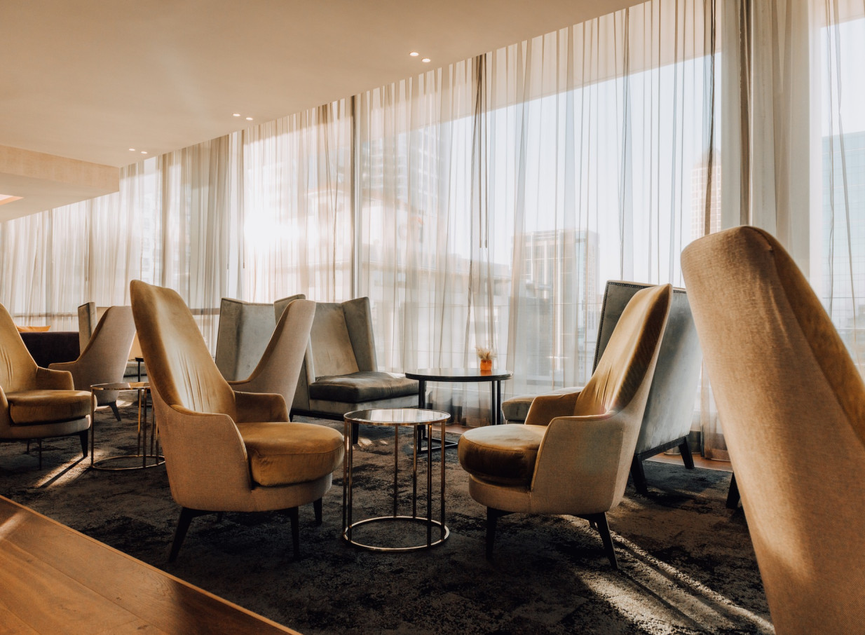 A modern and elegant lounge area with comfortable armchairs and large windows at the Mövenpick Hotel Auckland.