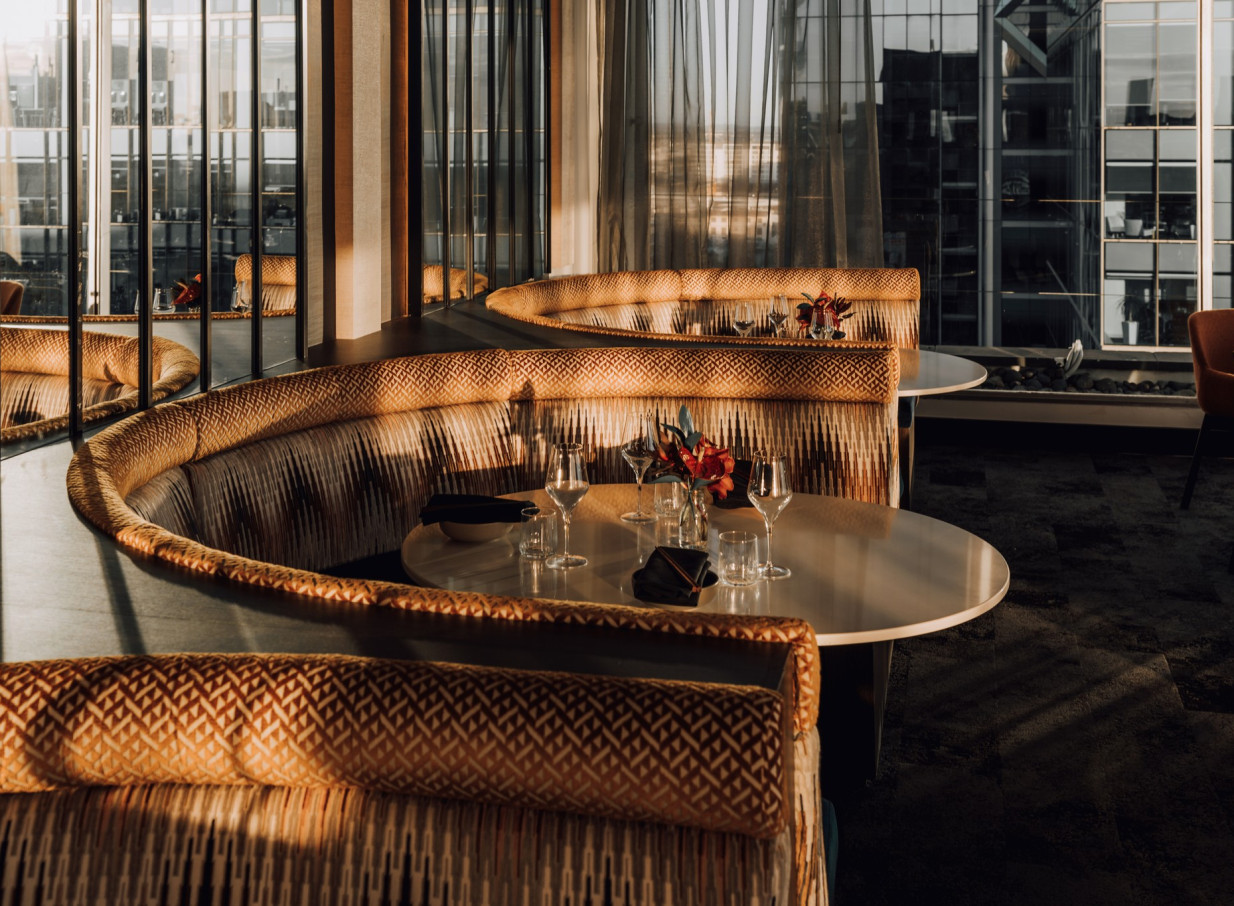 Modern Asian fusion dining at BODA, Mövenpick Hotel Auckland, boasts elegant booth seating with expansive city views.