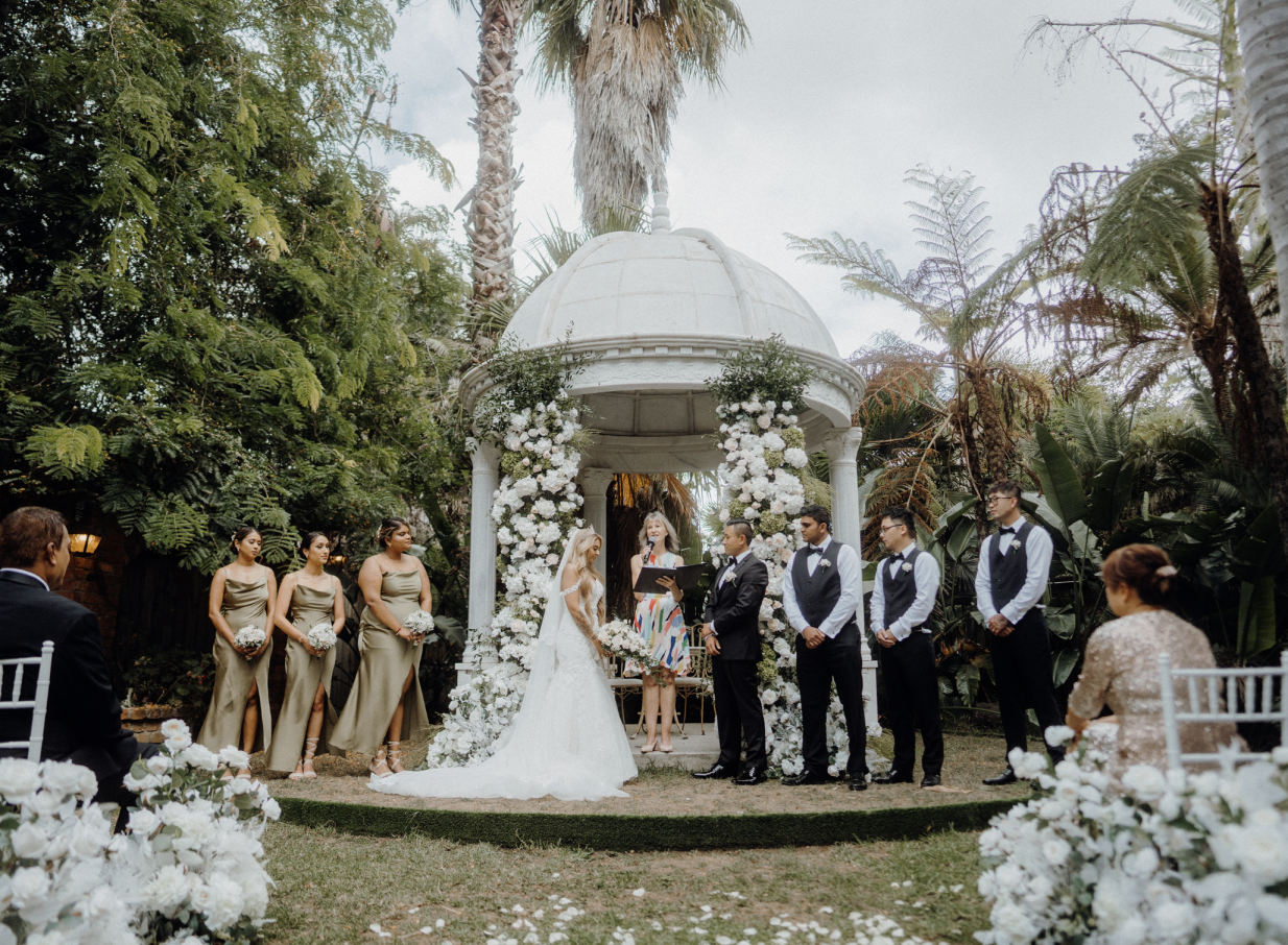 An outdoor ceremony takes place in the elegant garden gazebo of Settlers Country Manor, a heritage estate in Auckland.