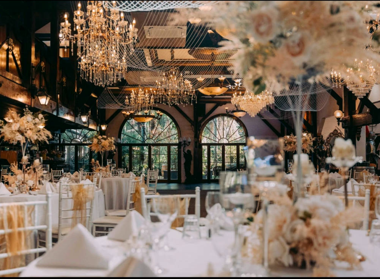 Settlers Country Manor, Auckland's heritage manor, hosts a vintage-elegant reception hall with grand chandeliers and arched windows.