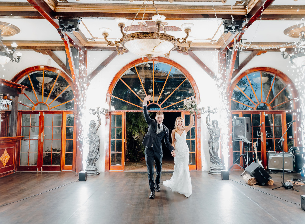 A couple makes a sparkler entrance in the elegant, vintage-style reception hall of Settlers Country Manor, Auckland.