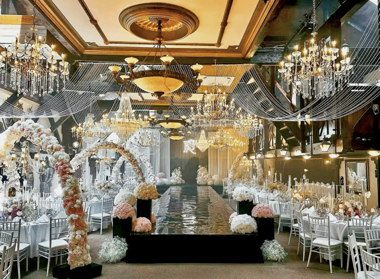 Settlers Country Manor, Auckland's vintage hall, set for an elegant event with ornate chandeliers and a reflective aisle.