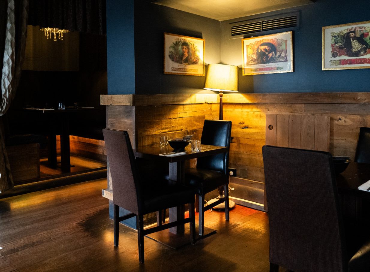 Casa Publica, Christchurch, offers a moody, South American-inspired dining area with warm lighting, wooden walls, and vintage art.