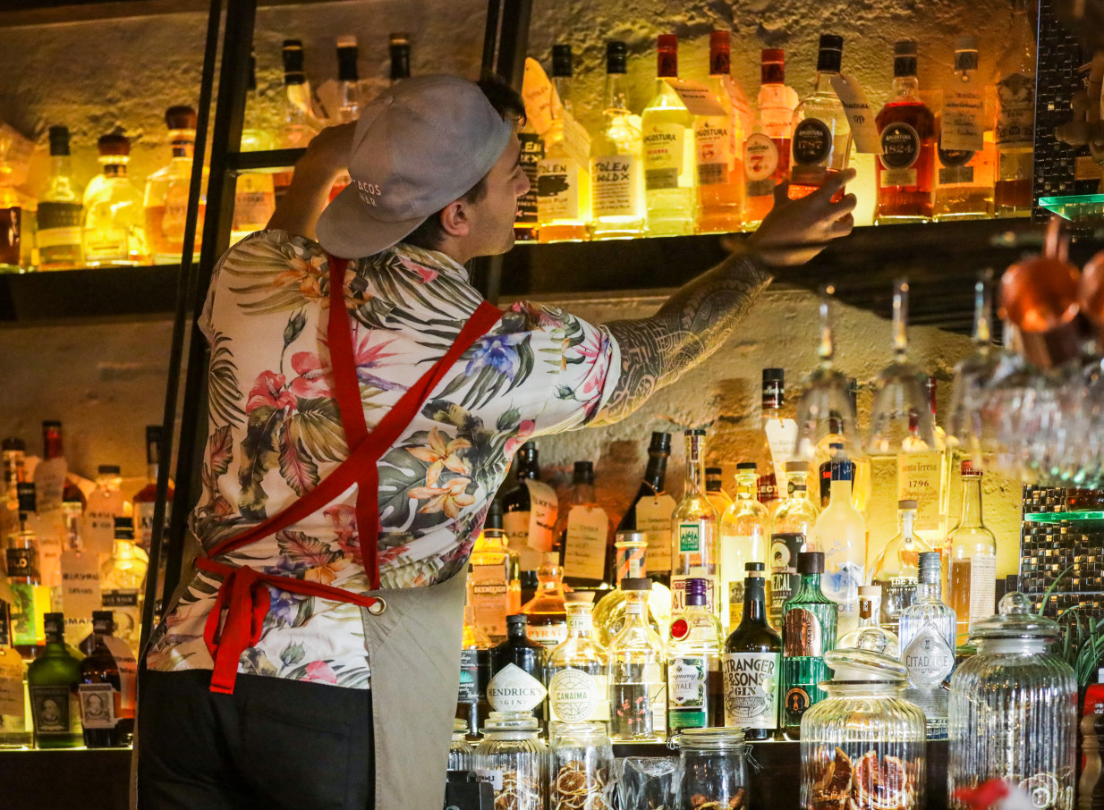 A bartender reaches for a bottle behind the illuminated, South American-inspired rum bar at Casa Publica in Christchurch.