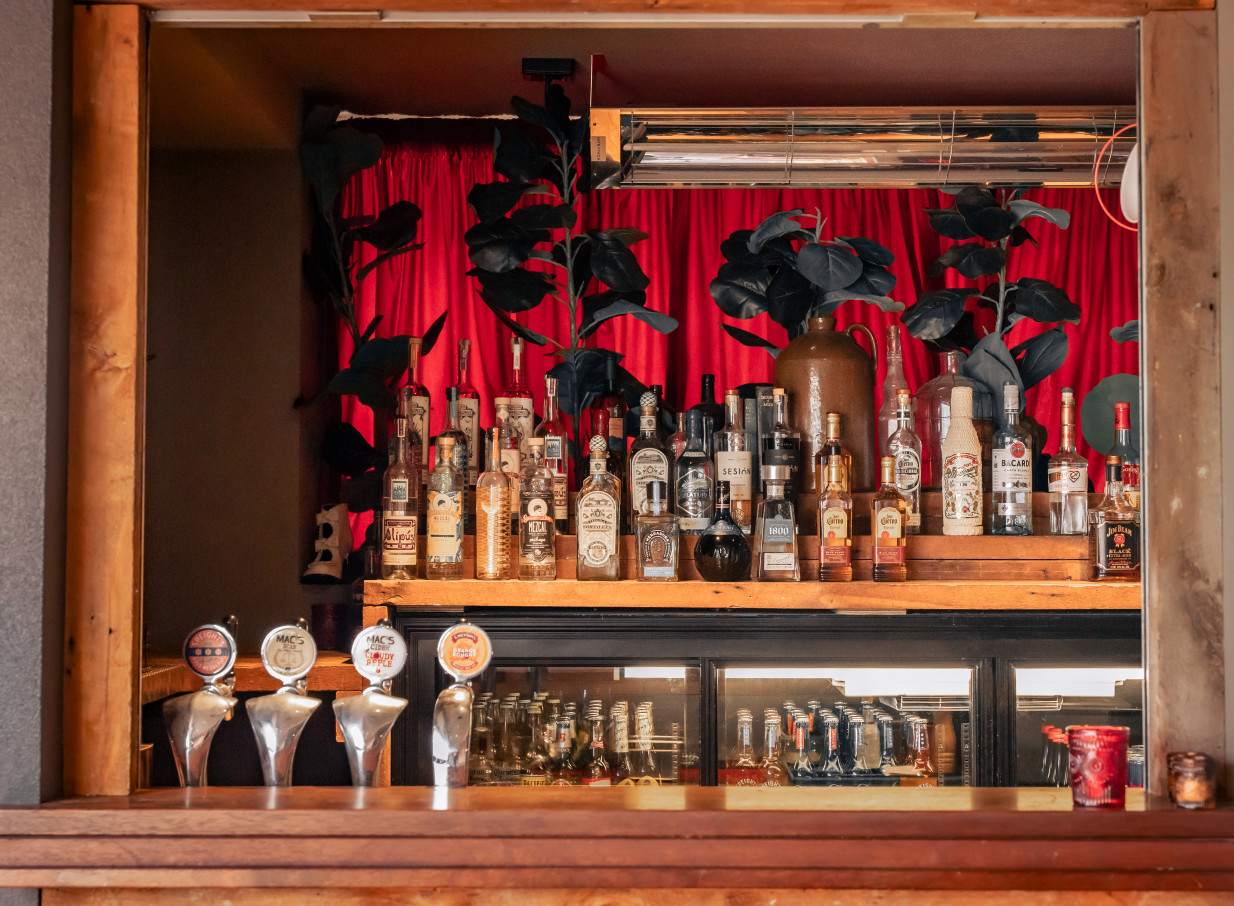 An old-world Latin American-inspired bar at Casa Publica in Christchurch, with red velvet curtains, spirits, and beer taps.