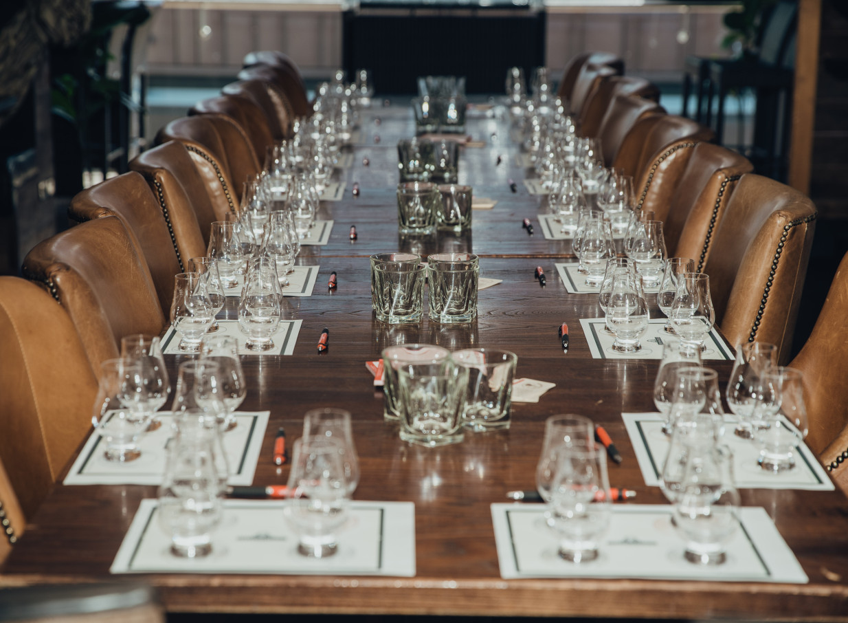 A long wooden table with tasting glasses and leather chairs in Casa Publica Christchurch's sophisticated, South American-inspired private dining space.