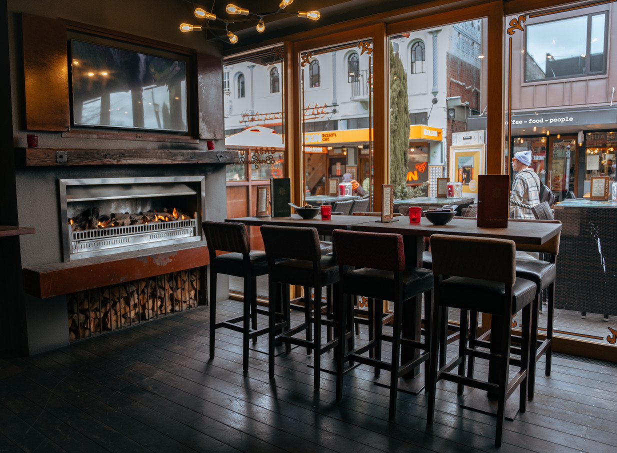Casa Publica, Christchurch's South American-inspired bar, features a cozy dining area with a fireplace and street view.