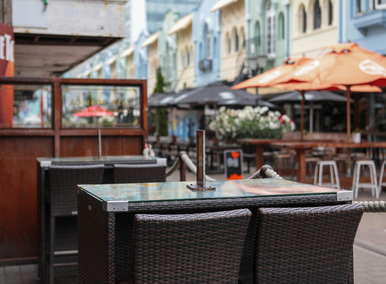 An inviting outdoor dining area with wicker furniture at the South American-inspired Casa Publica in Christchurch.