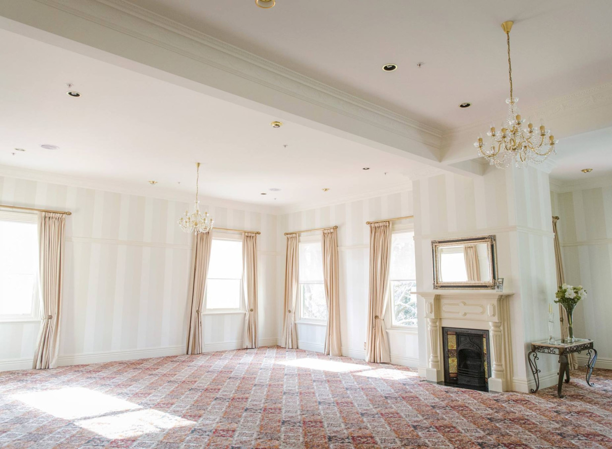 An elegant event room with chandeliers and a fireplace inside the historic Caccia Birch House in Manawatū-Whanganui.