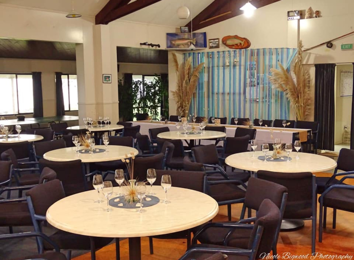 The Tauranga Fish and Dive Club's spacious event hall is set with round tables and coastal fishing decor for a relaxed gathering.