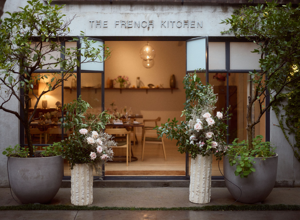 The elegant, glass-fronted entrance to The French Kitchen private dining room at The French Cafe, Auckland, with lush floral decor.