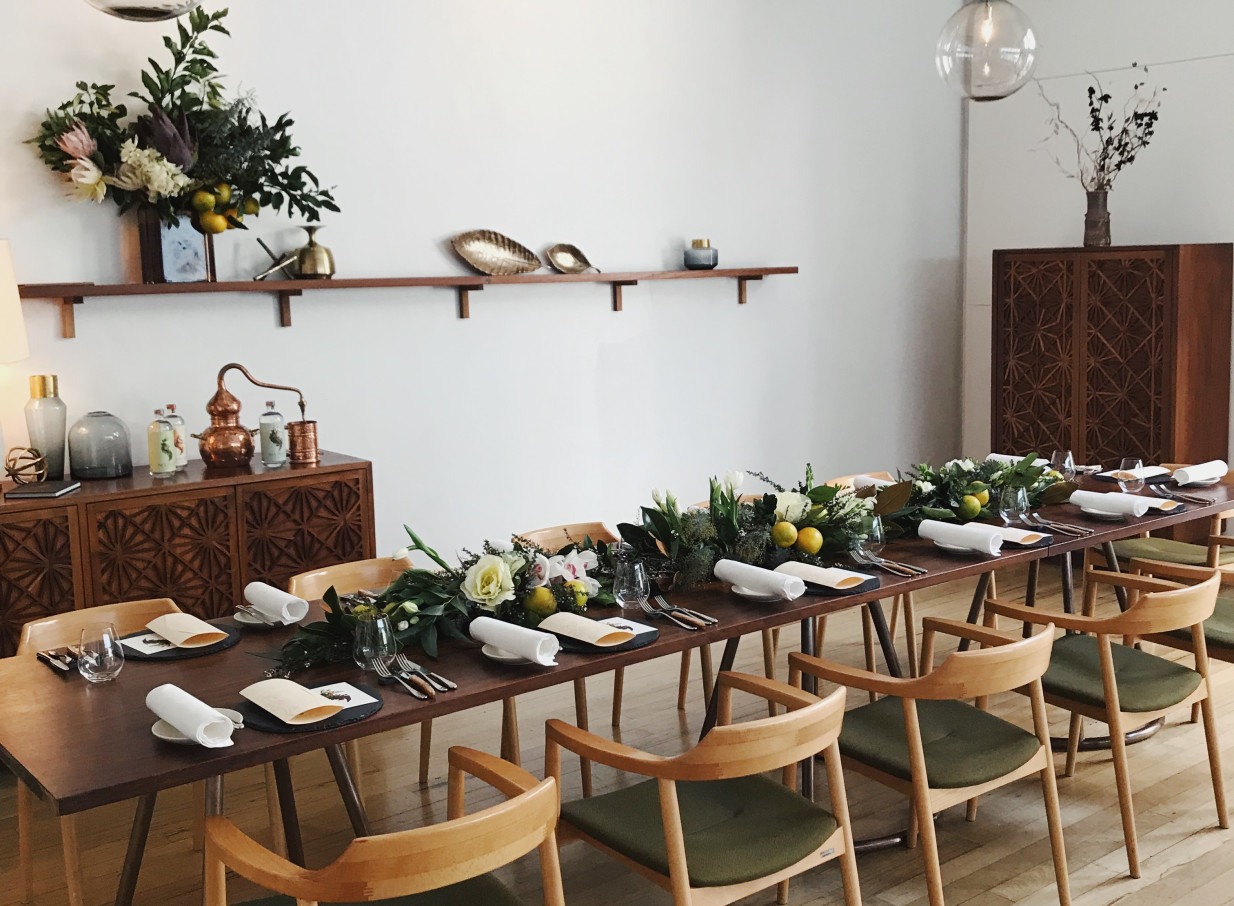 The French Cafe Auckland's refined private dining room features a long wooden table with an elegant floral and lemon centerpiece.