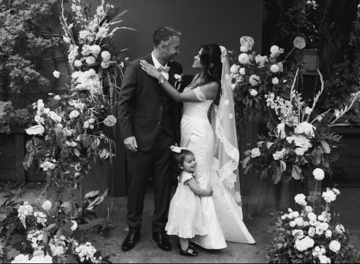 A classic wedding portrait taken in The French Cafe Auckland's elegant European-inspired courtyard, adorned with lush florals.