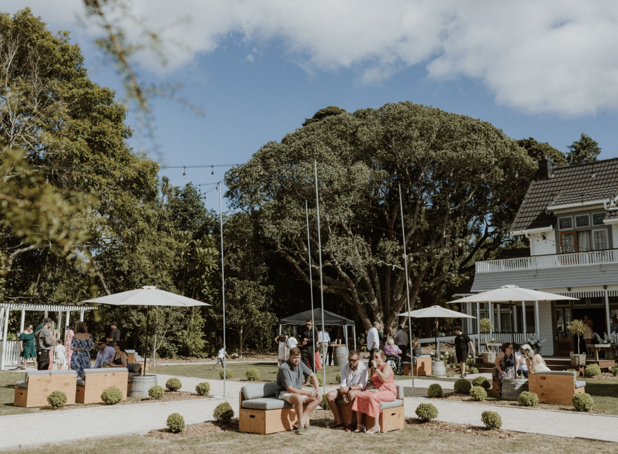 Guests socialize at an outdoor event in the lush gardens of Tatum, a historic homestead venue in Manawatū-Whanganui.