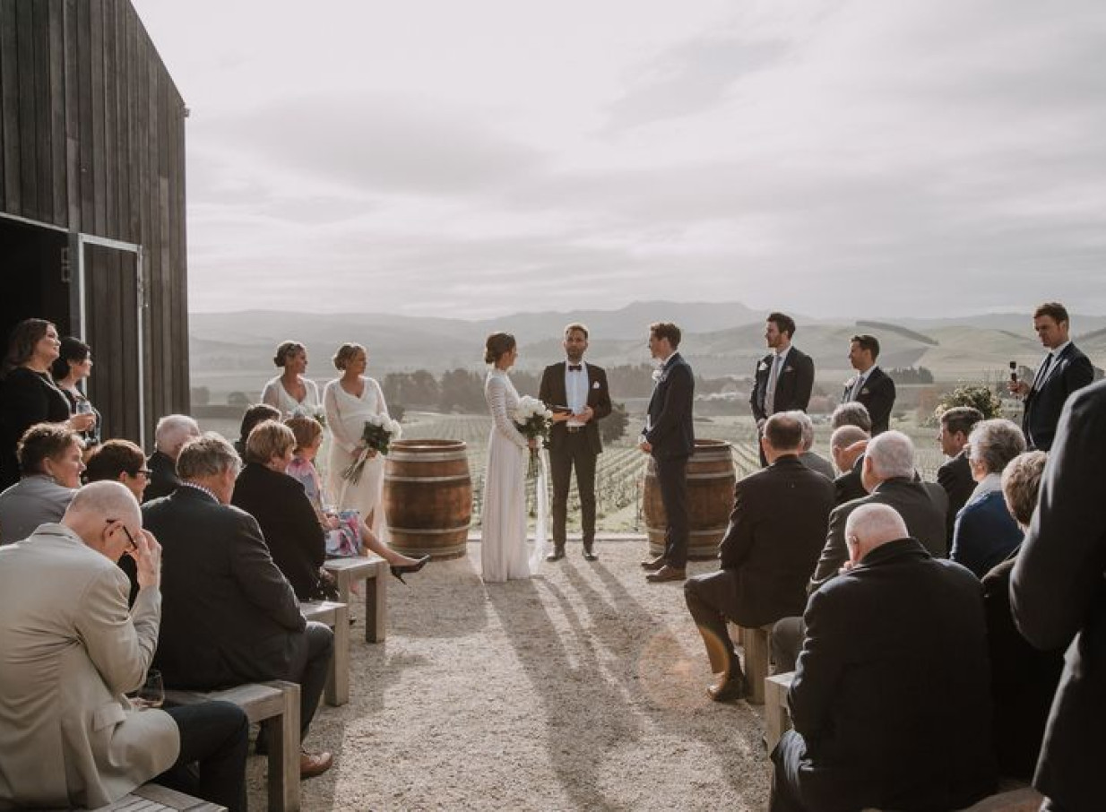 Outdoor ceremony at Black Estate Winery in Waipara, with its rural-shed inspired building and vineyard views.