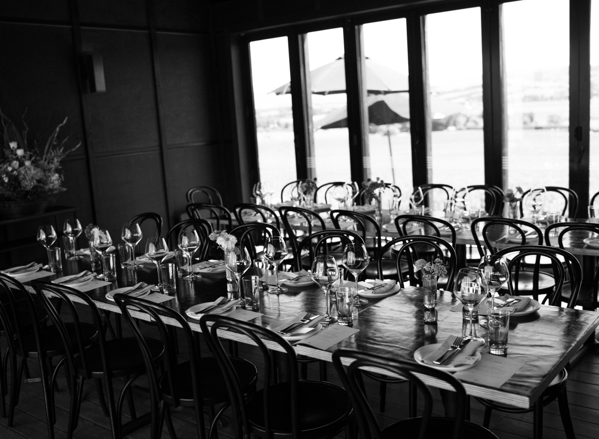 An elegant dining room, furnished with dark timber, overlooking the Waipara Valley vineyards at Black Estate Winery near Christchurch.