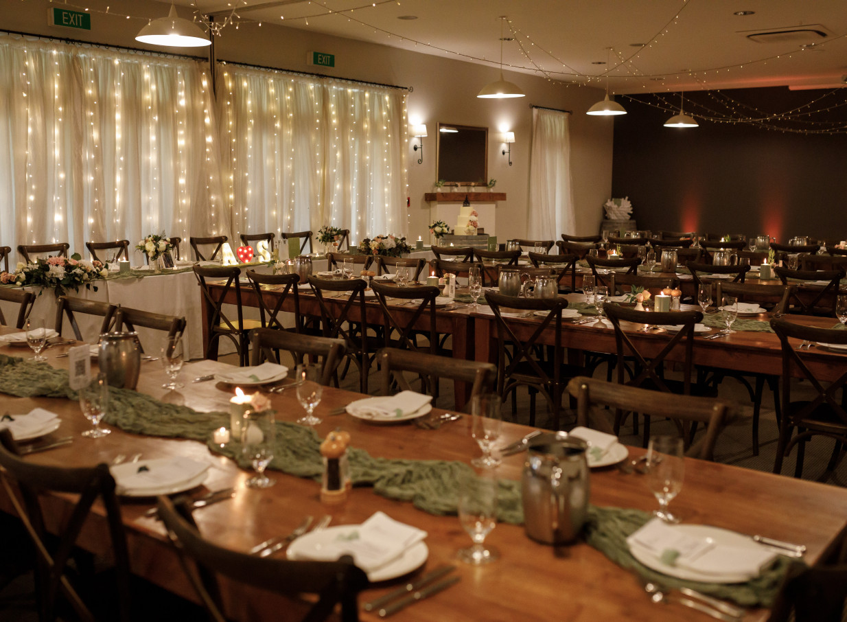 The country-style dining room at Brackenridge Country Retreat & Spa, Wellington, is beautifully set for a reception with long wooden tables and draped fairy lights.