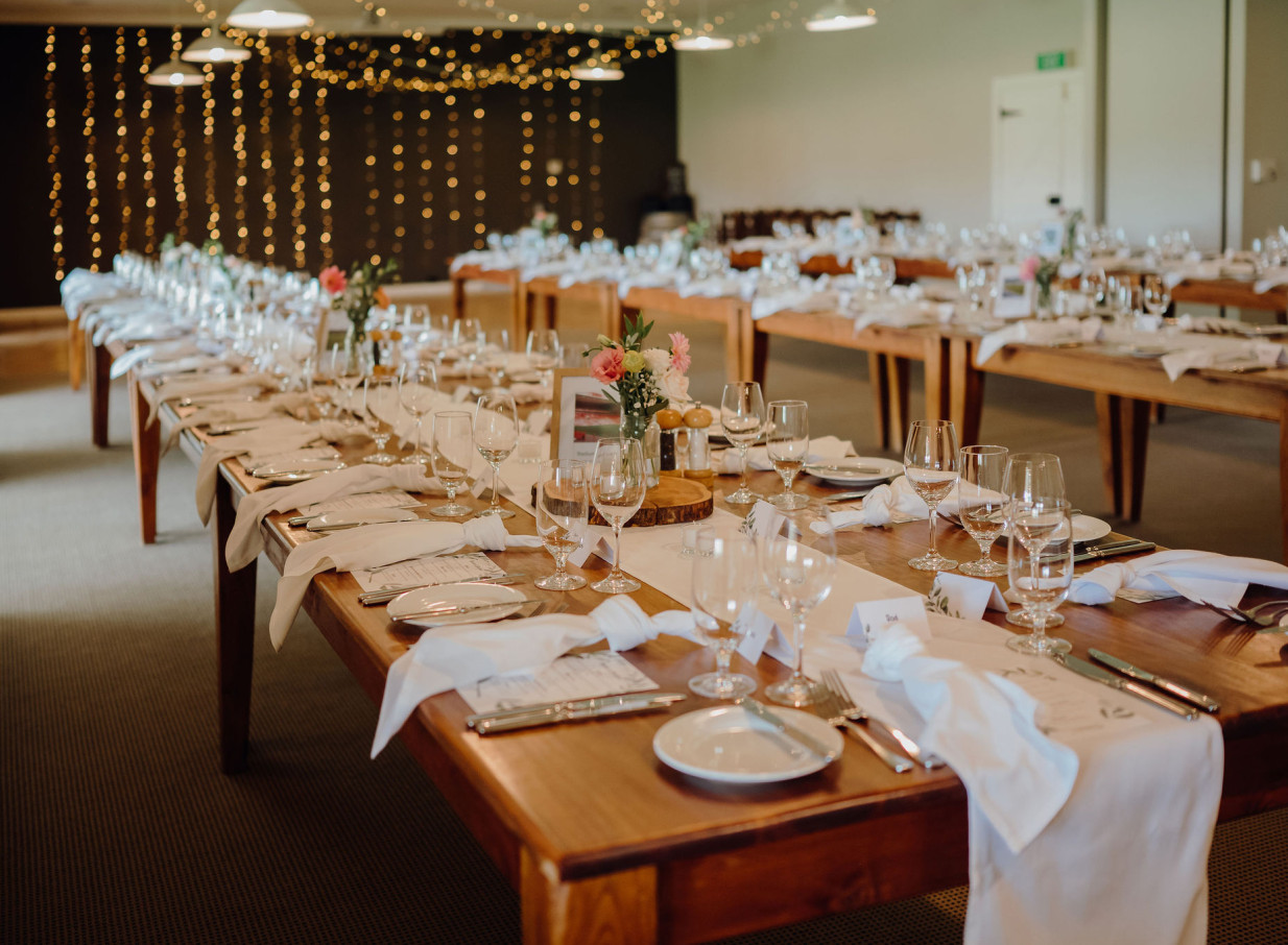 A country-style banquet room at Brackenridge Country Retreat & Spa, Martinborough, set for a festive event with long wooden tables and string lights.