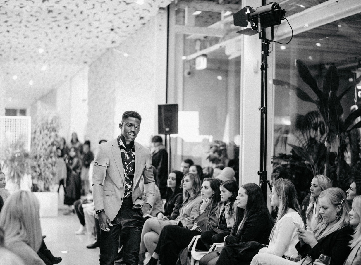 A model walks the runway during a fashion show at the contemporary architectural ilex venue in Christchurch, filled with natural light.