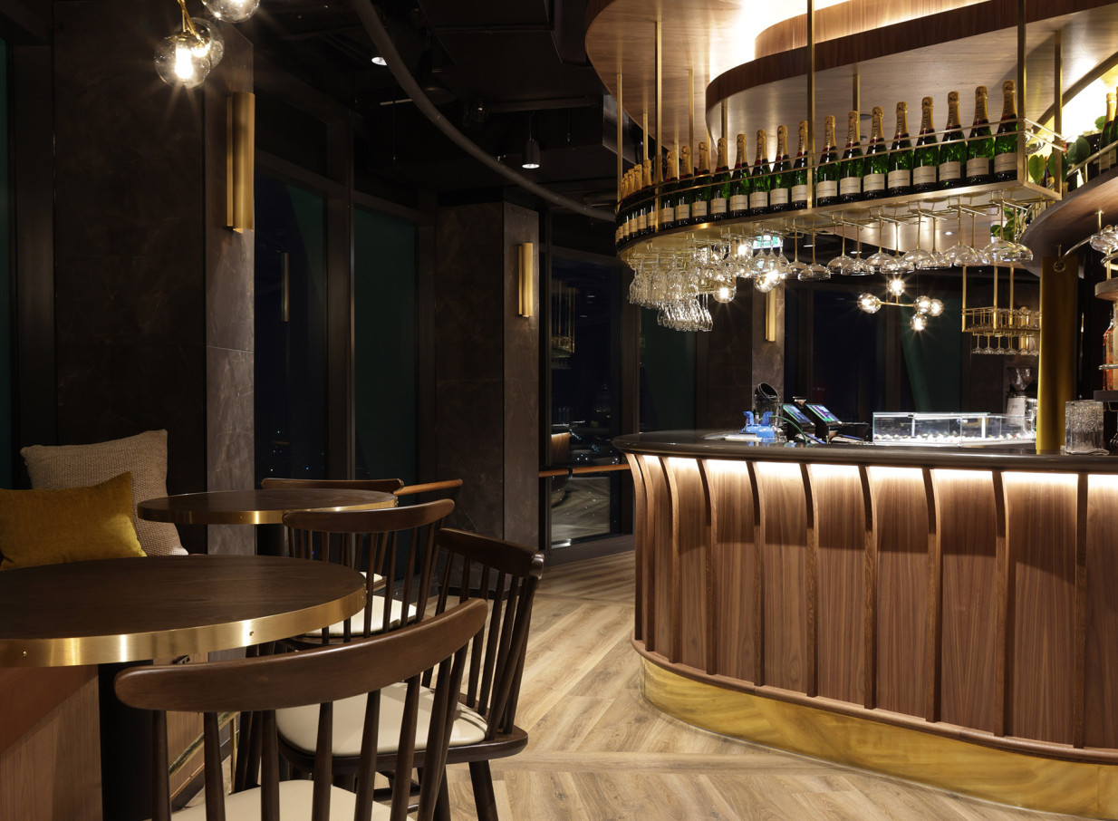 SkyBar Auckland, New Zealand's highest bar, presents an opulent lounge with a curved dark wood bar and brass details.