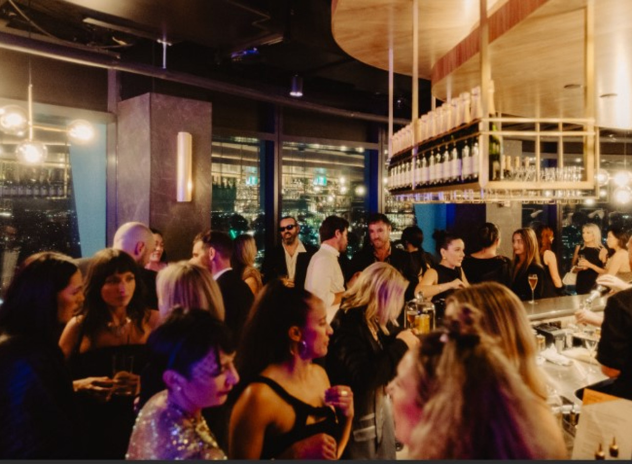 A glamorous, opulent sky-high bar at SkyBar Auckland, bustling with guests enjoying drinks and city views.