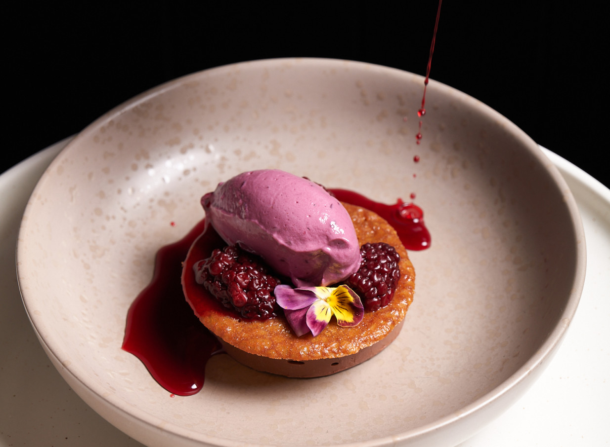 A vibrant dessert with purple ice cream and blackberries, embodying The Monday Room Christchurch's modern European-inspired cuisine in an intimate setting.