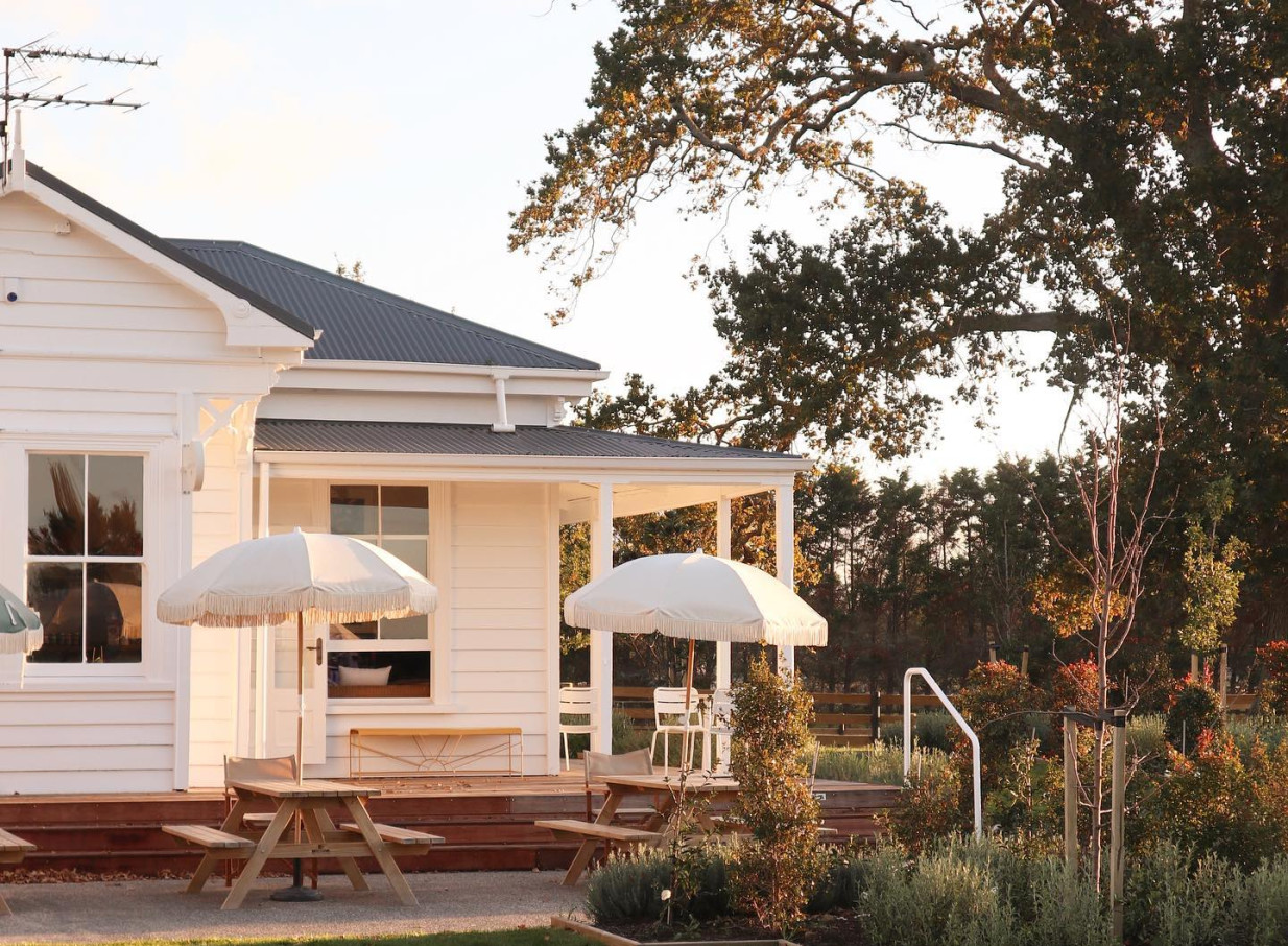 A relaxing outdoor patio with umbrellas at the charming white villa of Farm House Cafe in Auckland.