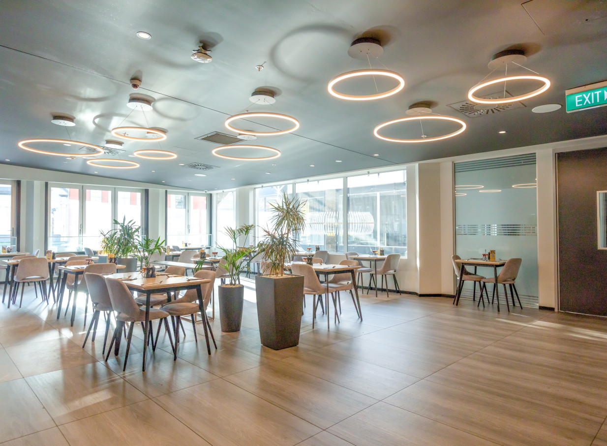 A modern dining room with circular pendant lights and large windows at the contemporary Oaks Wellington Hotel in Wellington.