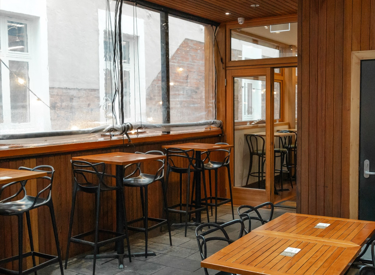 An inviting modern industrial-chic enclosed patio bar area with wooden details at Amador at Press Hall in Wellington.