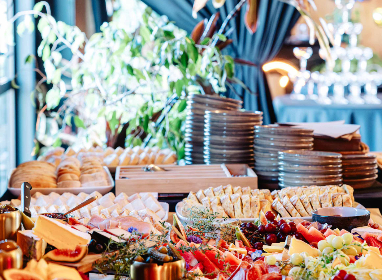 A vibrant grazing table, featuring diverse fare, within Evil Genius Christchurch's rustic, lushly green event space.