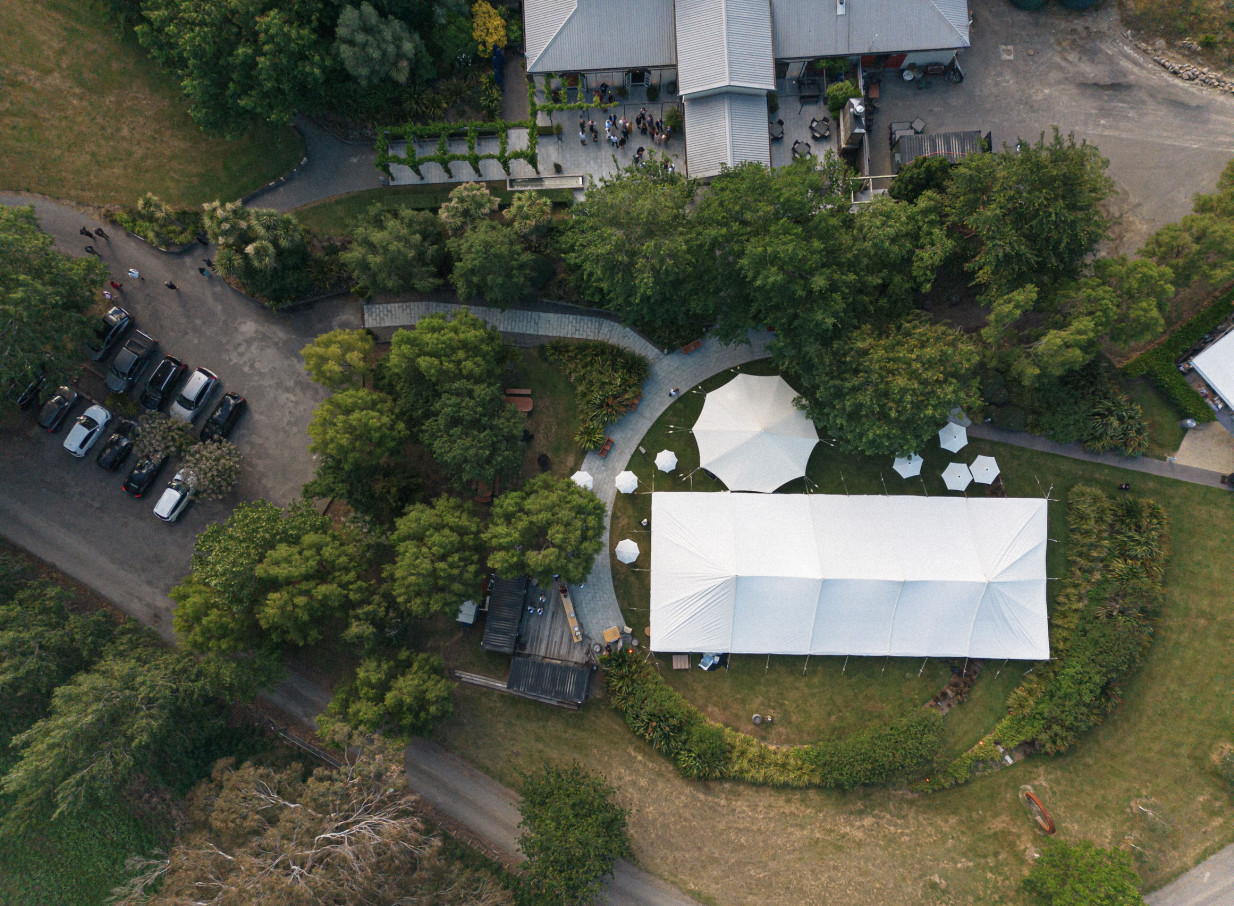 A large outdoor event tent and smaller marquees are set amidst the lush gardens of Parehua Resort, Martinborough.
