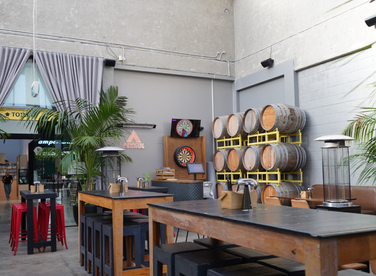 An industrial-chic lounge with dartboards and barrel decor at Orakei Local, Auckland, offering a relaxed neighbourhood vibe.