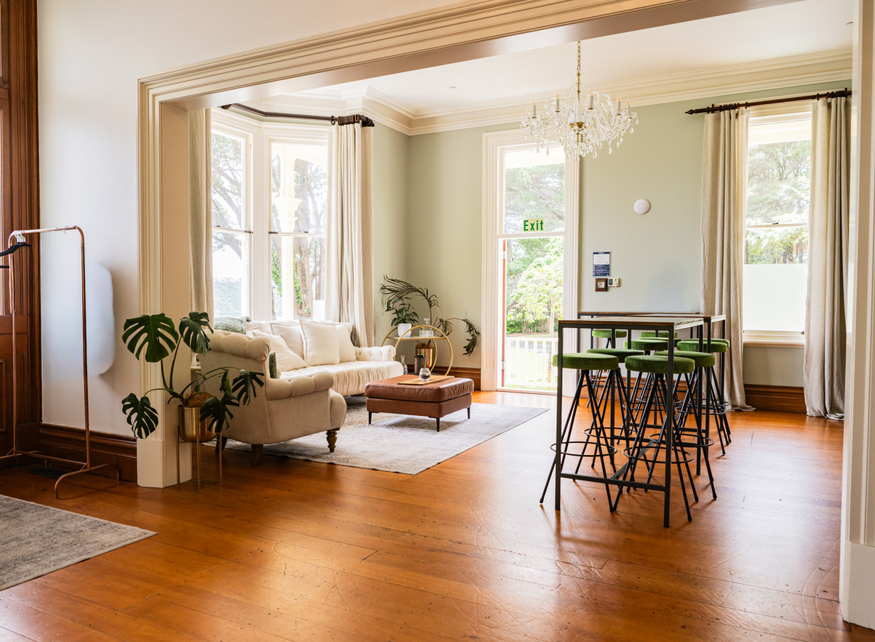 The elegant, historic lounge at Gear Homestead in Wellington features high tables and plush seating, embodying its Victorian charm.