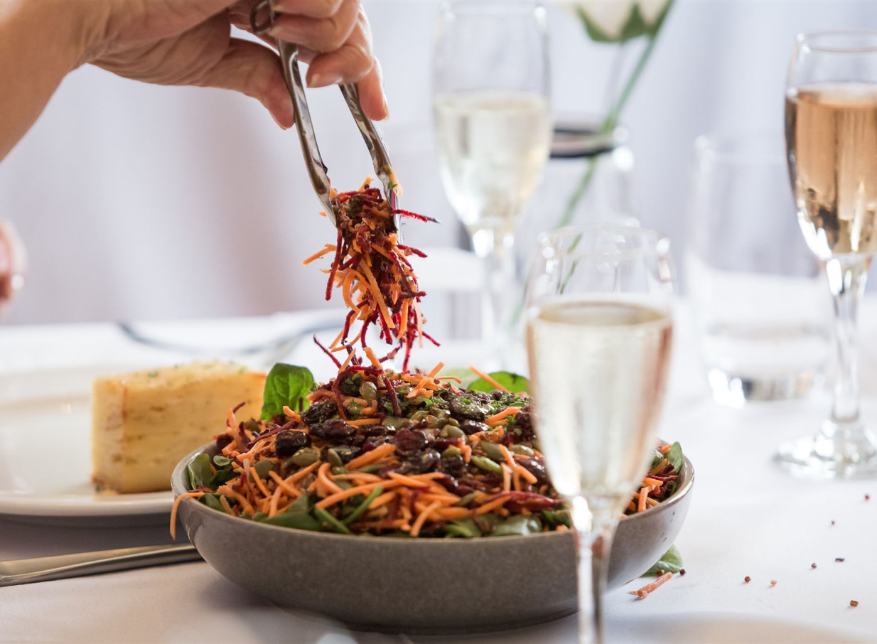 A fresh salad is being served at a dining table within Wellington's elegant, historic Gear Homestead.
