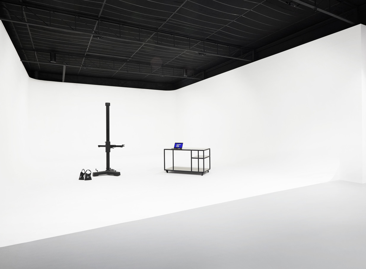 A minimalist white cyclorama photography studio with a black ceiling, complete with a light stand and mobile workstation, at Common Space Studios in Auckland.
