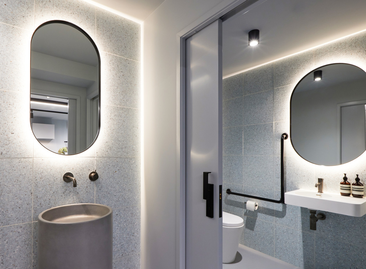 This luxurious and modern bathroom at Common Space Studios in Auckland features sleek oval backlit mirrors.