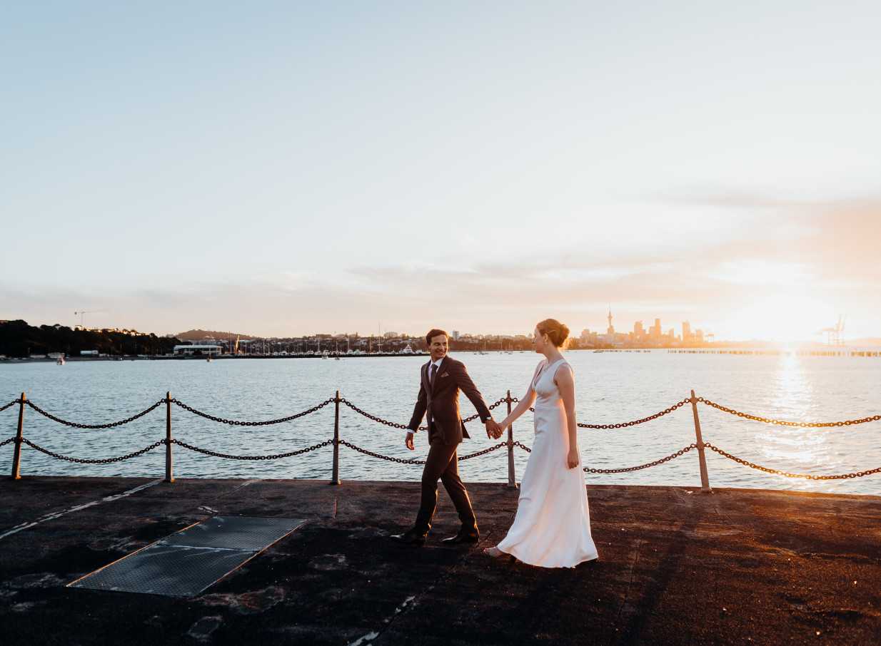 A couple at Antlia, Auckland's heritage waterfront venue, enjoys a sunset moment with the city skyline.