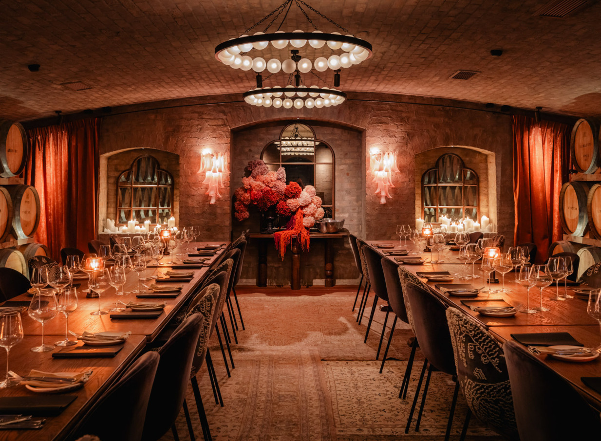 An elegant private dining experience in Ayrburn Queenstown's heritage Barrel Room, with rustic stone walls and candlelit tables.