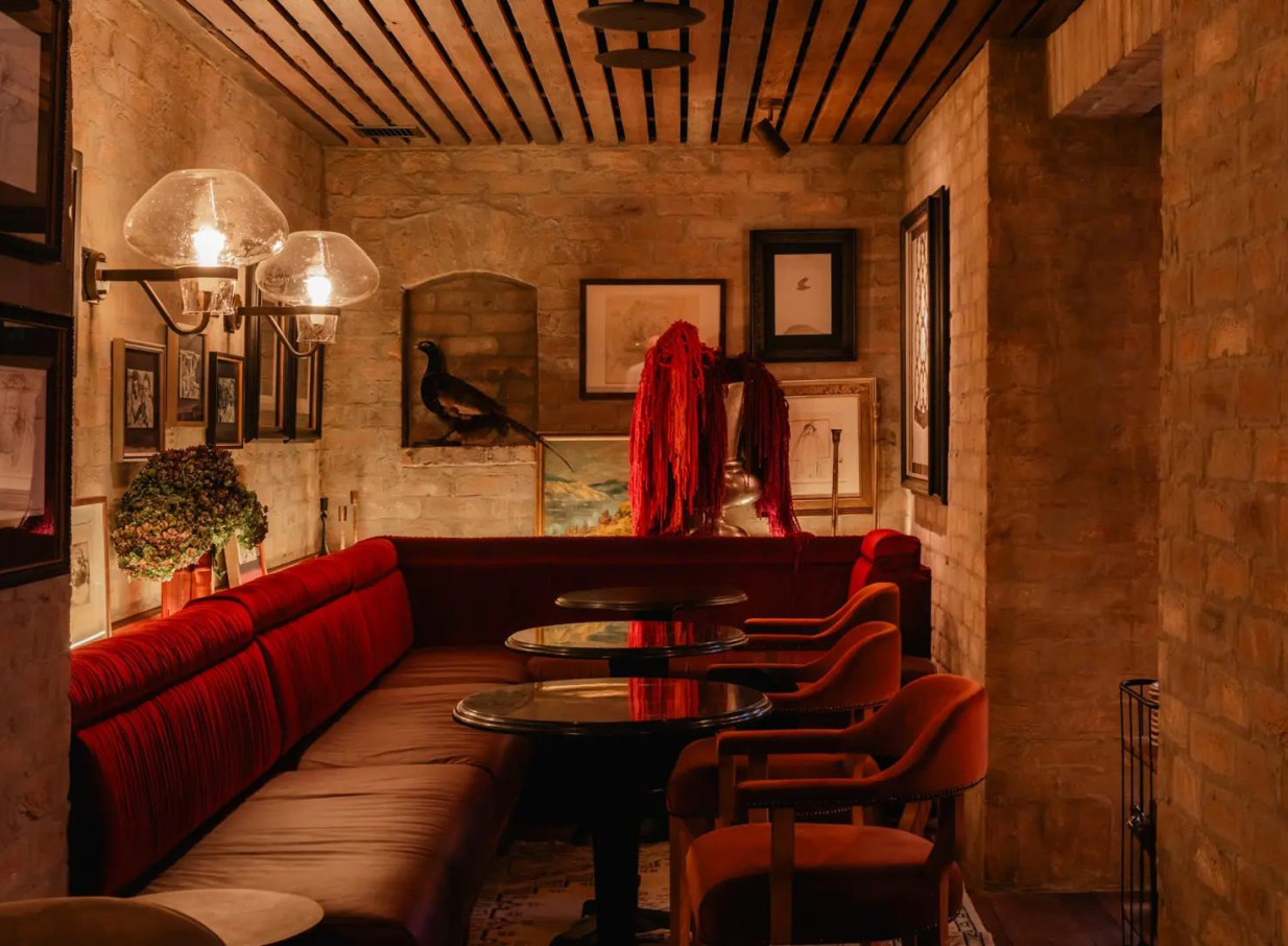 The intimate Burr Bar at Ayrburn, Queenstown, features heritage-chic exposed brick and plush red velvet seating.