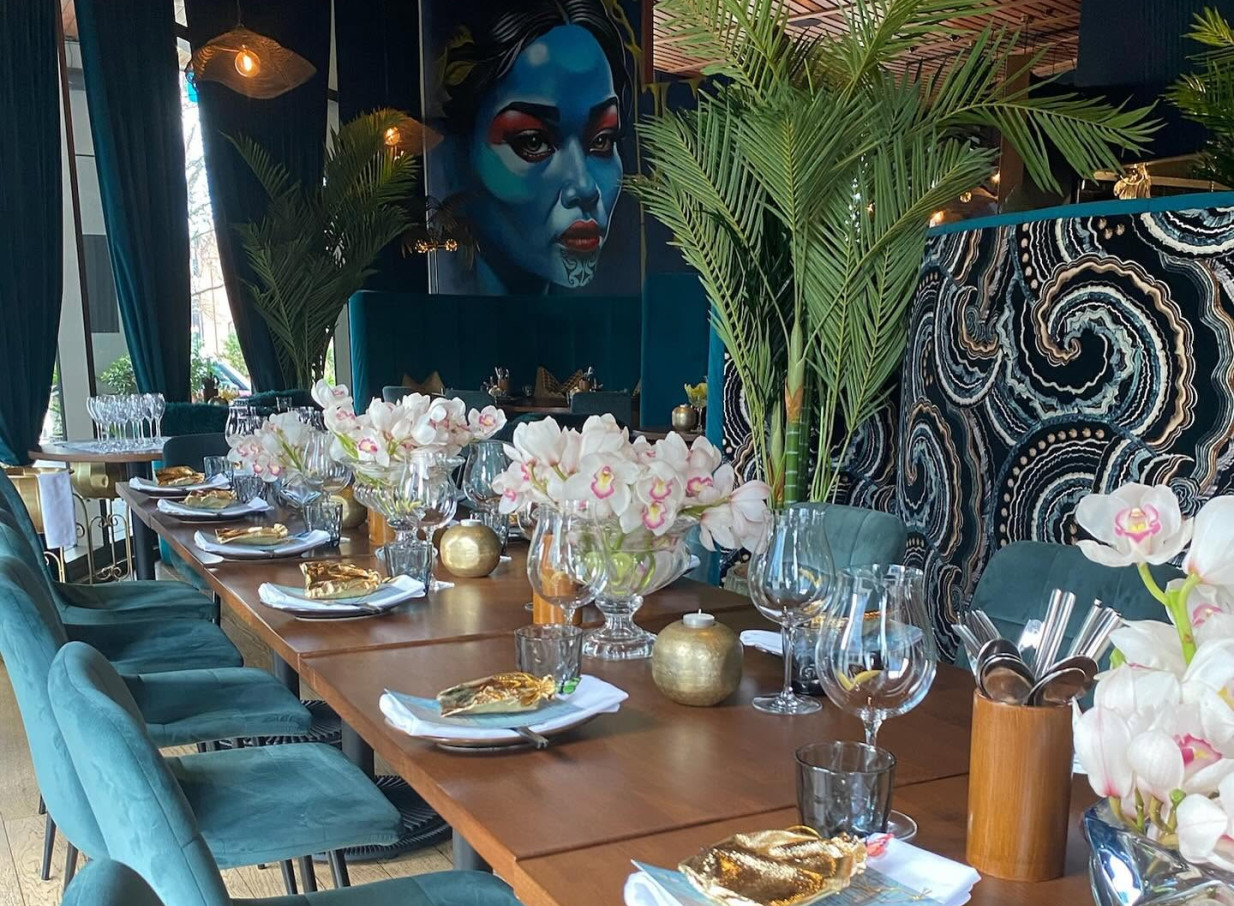 This vibrant, Pacifica glam private dining room at Manu in Christchurch features bold artwork and lush greenery.
