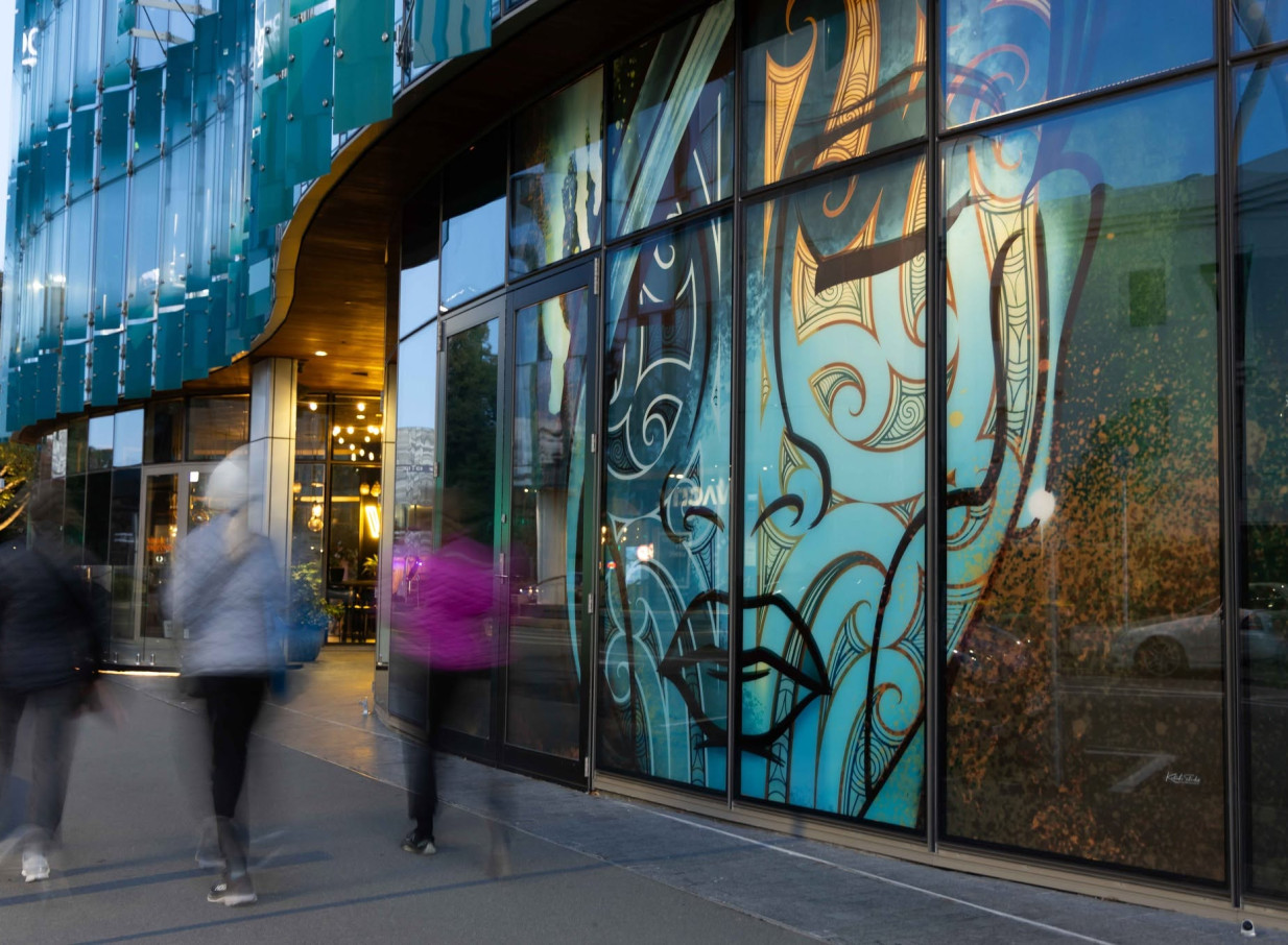 Manu in Christchurch presents a modern exterior, adorned with vibrant, culturally-inspired artwork across its large glass windows.
