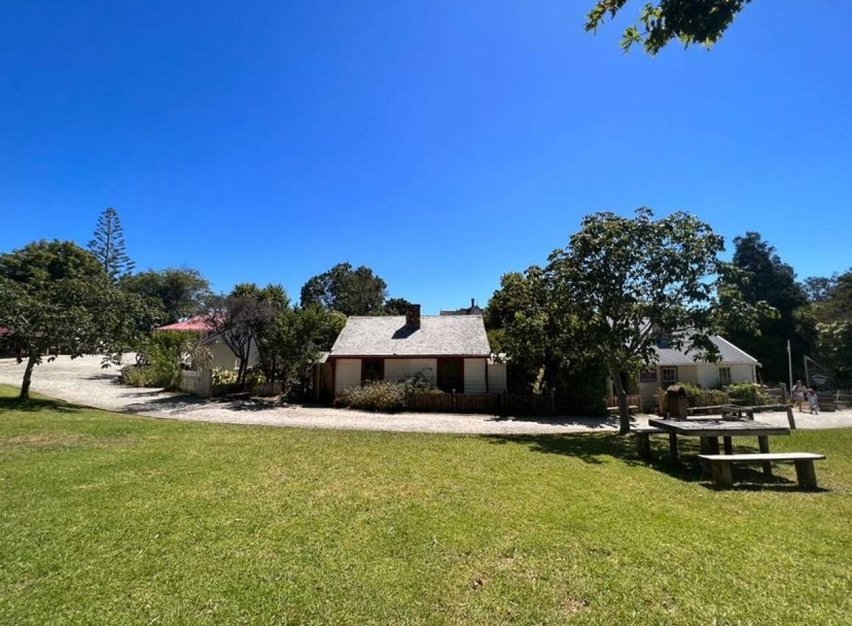 An outdoor scene at Howick Historical Village, Auckland, featuring colonial-style Fencible settler buildings and a picnic area.