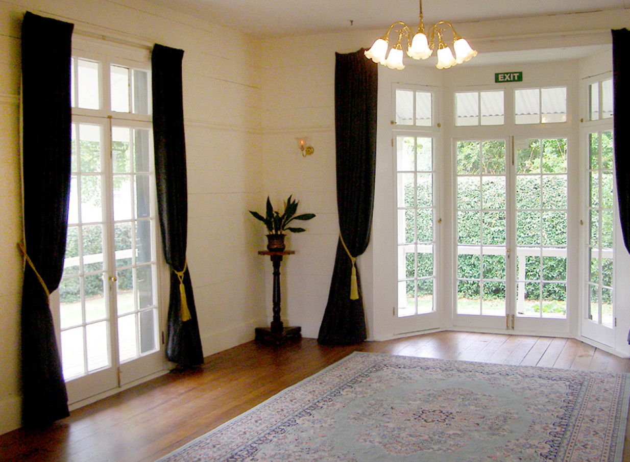 The elegant colonial-era room at Howick Historical Village, Auckland, with French doors opening to gardens.