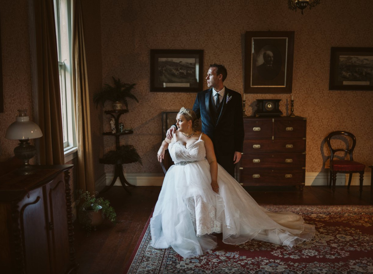 A newlywed couple poses in a colonial-era interior at Howick Historical Village in Auckland.