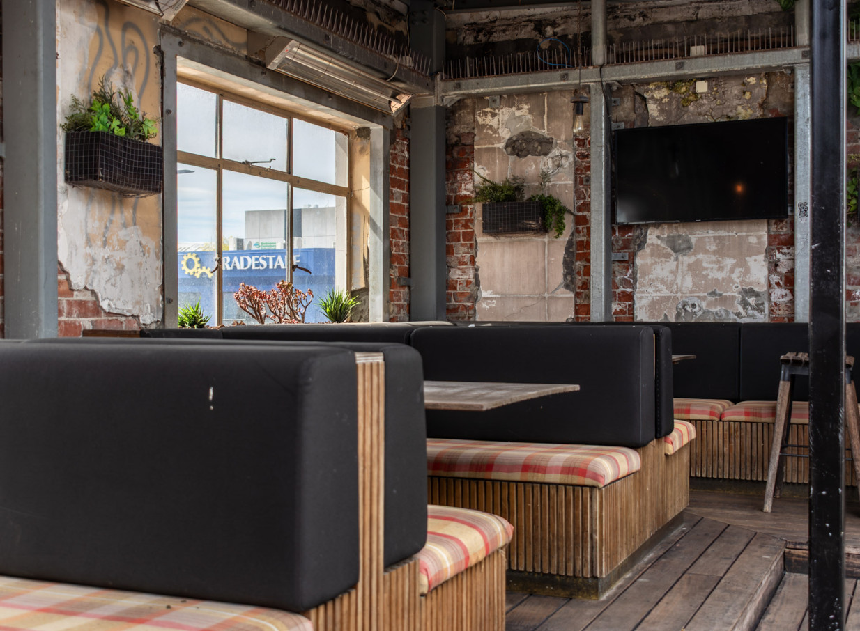 An indoor seating area with exposed brick, timber booths, and a modern industrial aesthetic at Royals Christchurch.