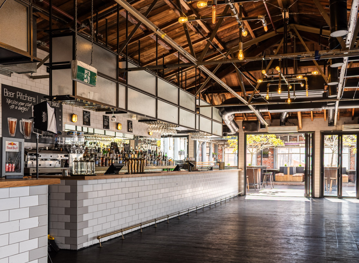 An industrial-chic bar and event space at Royals Christchurch features exposed timber, metalwork, and outdoor access.
