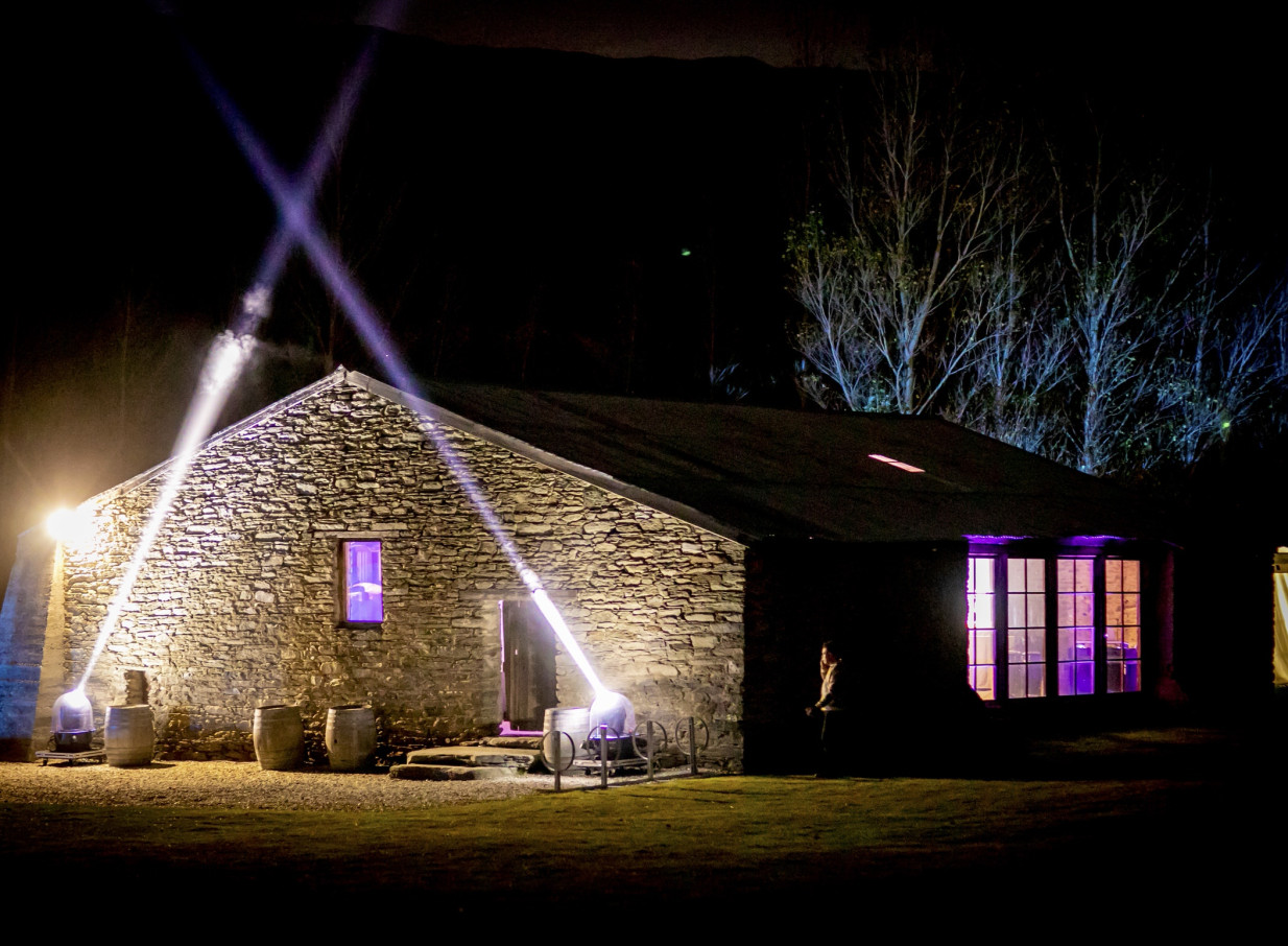 Peregrine Winery's historic 1860s schist stone woolshed in Queenstown, bathed in dramatic purple event lighting at night.