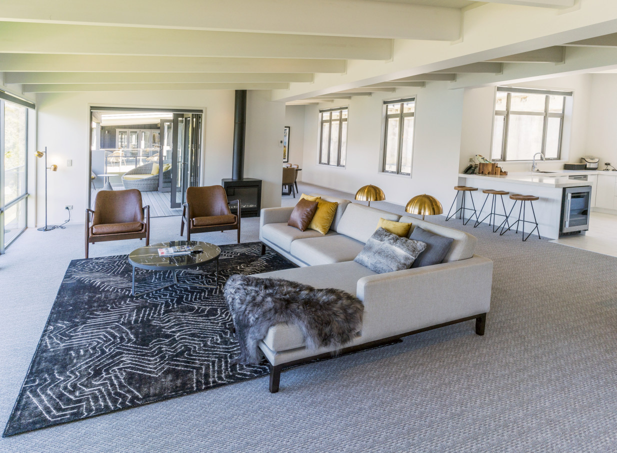 A contemporary alpine-inspired living space with exposed beams at The Rees Hotel, Apartments & Residences in Queenstown.