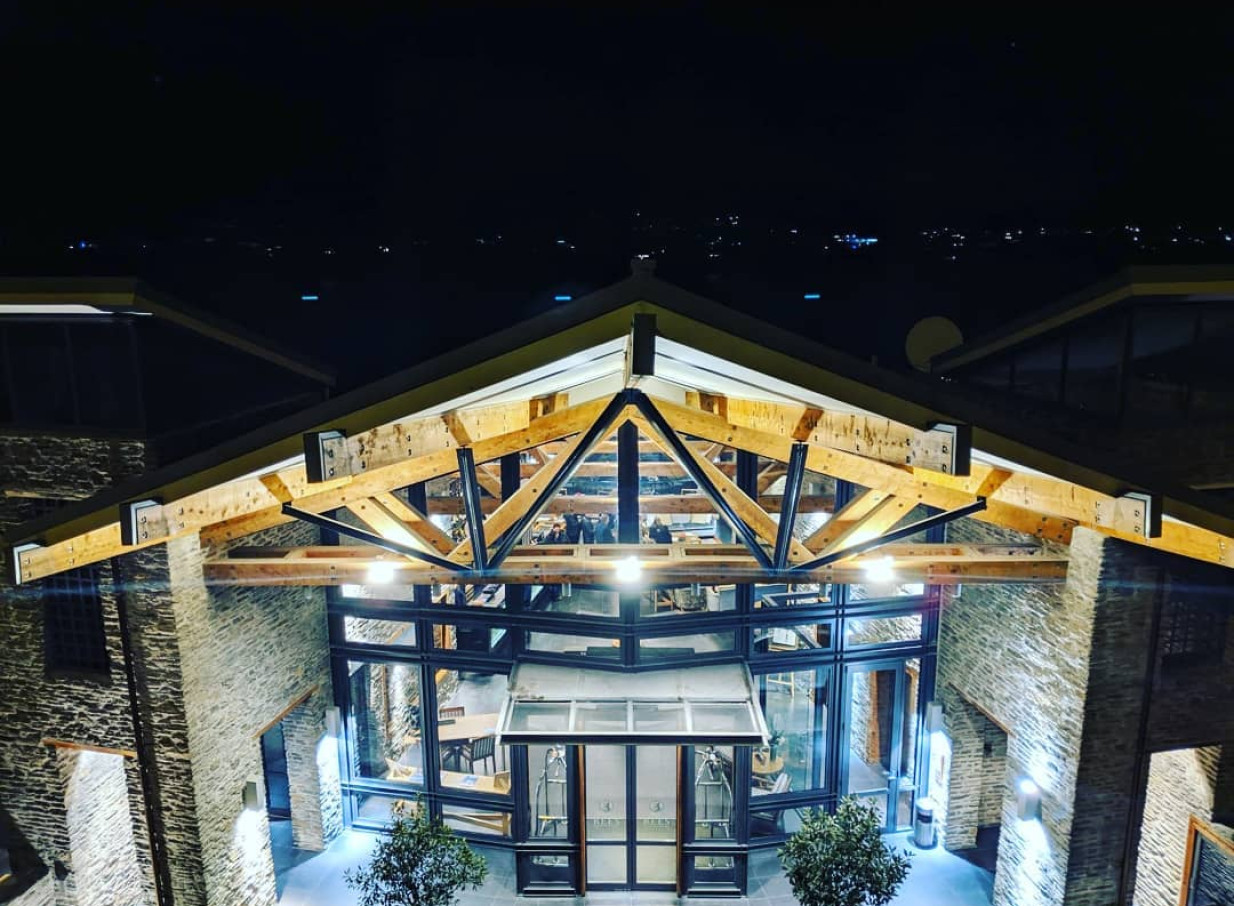The Rees Hotel, Apartments & Residences in Queenstown showcases its modern, rugged entrance at night, with solid beams and handcrafted stone.