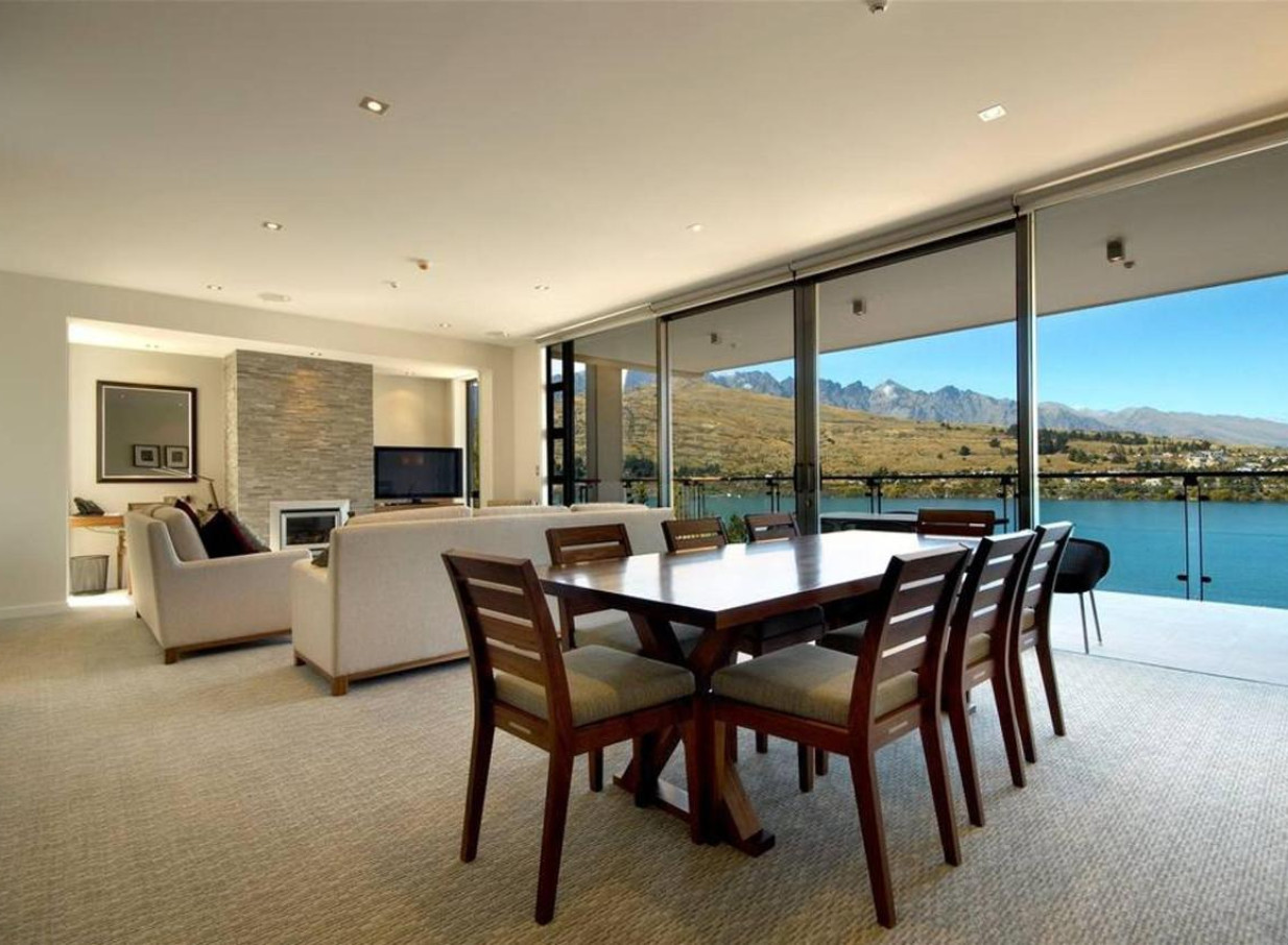 A stylish open-plan living and dining area at The Rees Hotel Queenstown offers panoramic lake and mountain views.